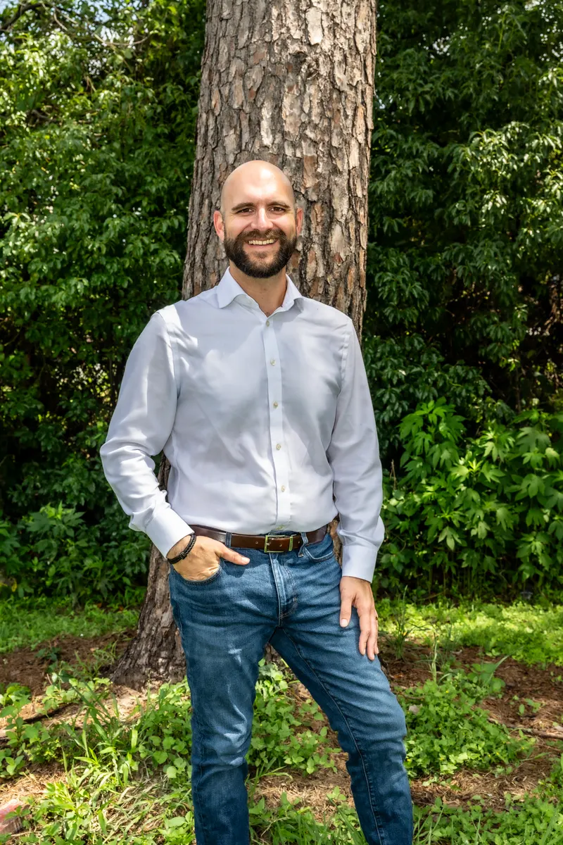 Nic Zateslo standing outdoors beside a pine tree